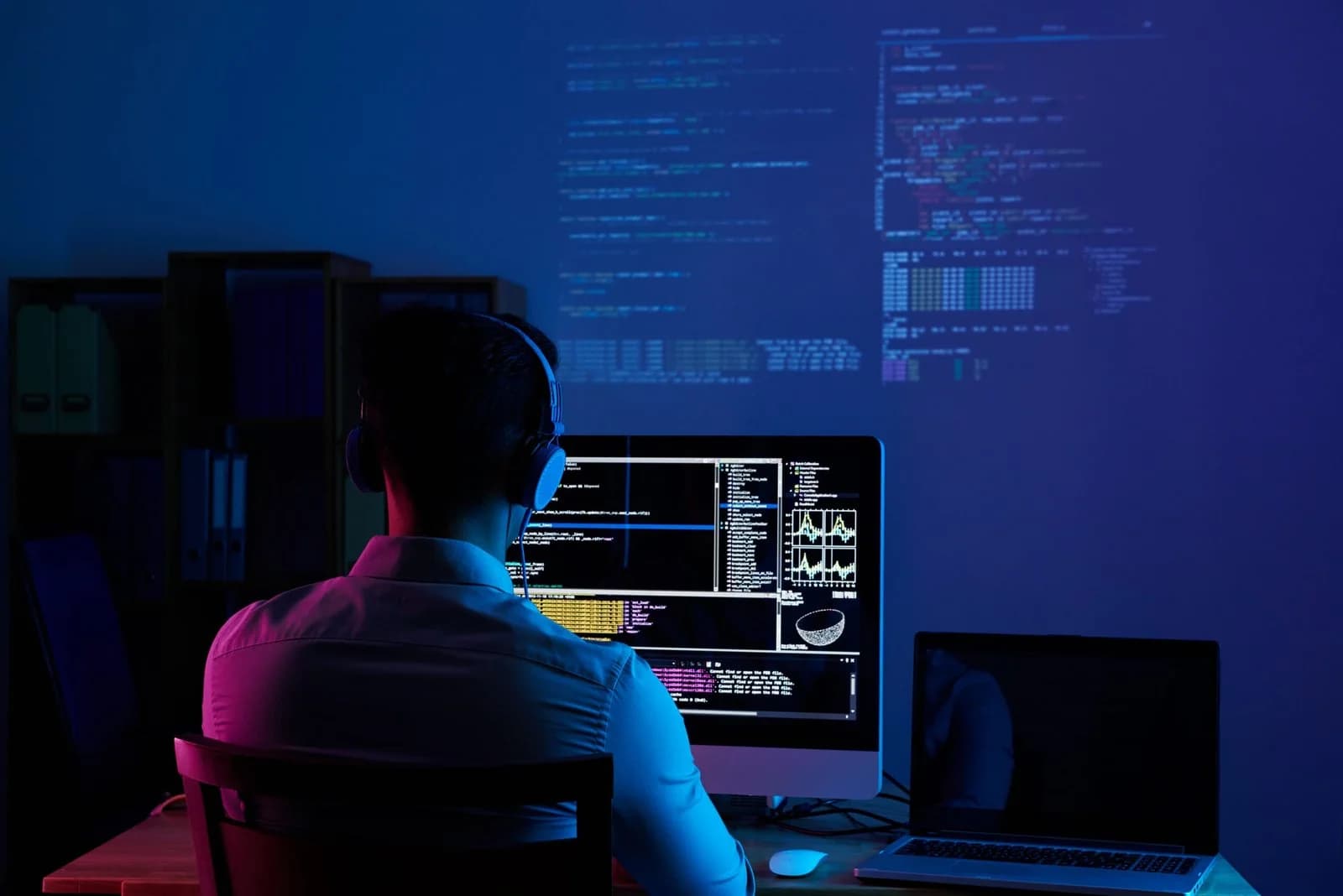 Developer working at a desk with code displayed across several screens